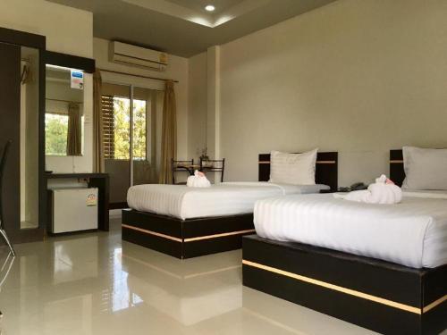 a bedroom with two beds with white sheets at Baan Ing Daan in Ban Non Nam Thaeng