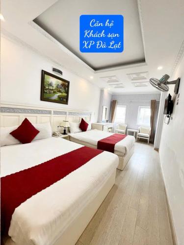two beds in a hotel room with a sign on the ceiling at Khách Sạn Căn Hộ XP -Đà Lạt in Da Lat