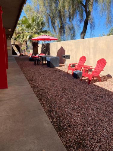 zwei rote Stühle und ein Tisch mit Sonnenschirm in der Unterkunft Oasis in Phoenix