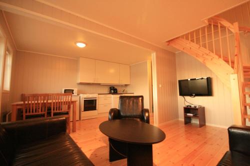 a living room with a couch and a table and a kitchen at Sarnes Seaside Cabins in Honningsvåg