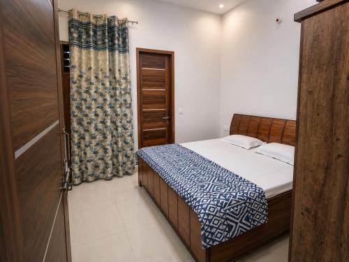 a small bedroom with a bed and a curtain at Palam Villa in Kharar