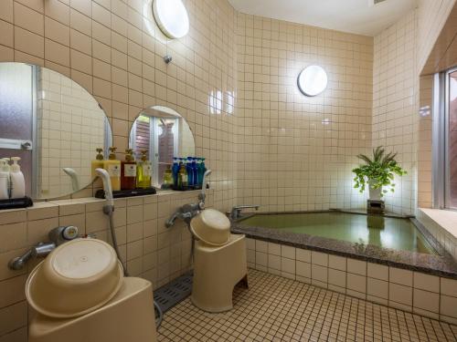 a bathroom with a tub and a toilet and a sink at Petit Resort Hotel Alcyon in Ito