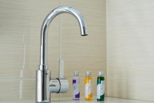 a bathroom sink with a faucet with three bottles at Hotel Beck in Lauscha - Ernsthal am Rennsteig