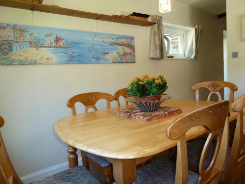 a dining room table with chairs and a vase of flowers on it at The Old Shippon in Bude