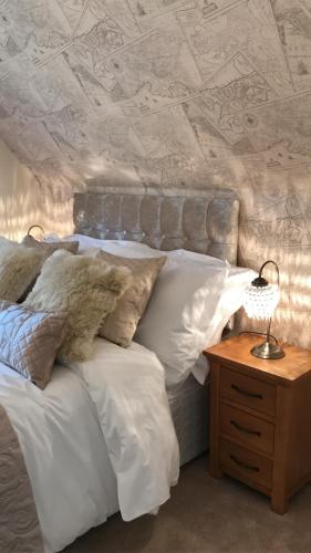 a bedroom with a bed with white pillows and a table at Luxury 3 Bed Home by the Lake in South Cerney