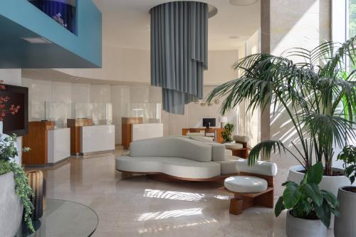a living room with a white couch and some plants at Meliá Lisboa Oriente in Lisbon