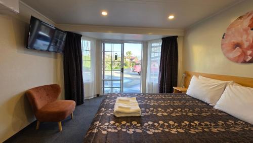 a hotel room with a bed and a tv on the wall at Admirals Motor Lodge in Blenheim