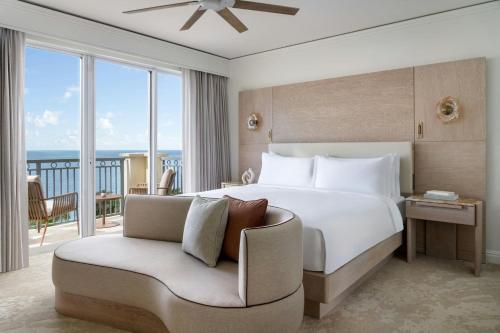 a bedroom with a bed and a chair with a balcony at The Ritz-Carlton Key Biscayne, Miami in Miami