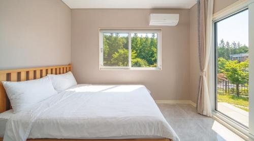 a bedroom with a white bed and a window at Daebudo Freesia Private Pool Villa in Ansan