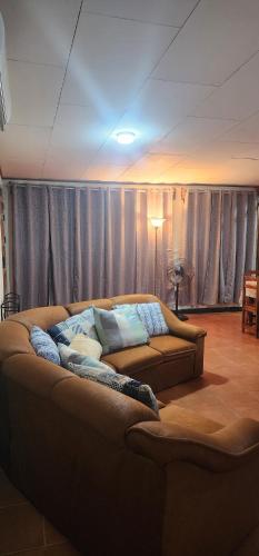 a couch sitting in a living room with curtains at Comfortable fully equipped apartment just 6 kilometers from Manuel Antonio, with parking and fast WiFi in Quepos