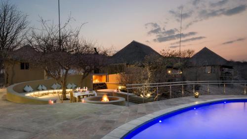 a backyard with a swimming pool and a house at Safarihoek Lodge in Kamanjab