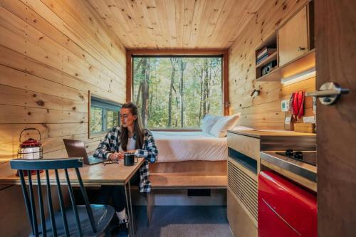 a woman sitting at a table in a tiny house at Postcard Cabins Starved Rock, Outdoor Collection by Marriott Bonvoy in Ottawa
