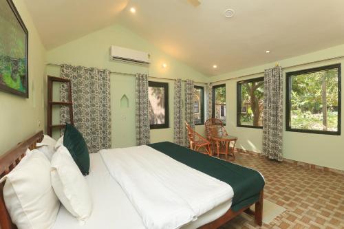a bedroom with a large bed in a room with windows at Sariska Forest Trail in Rāmsinghpura
