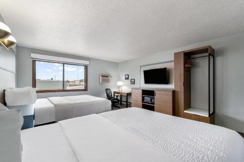 a hotel room with two beds and a flat screen tv at AmericInn by Wyndham Cloquet in Cloquet
