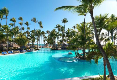 a swimming pool with palm trees in a resort at Meliá Caribe Beach Resort - All Inclusive in Punta Cana