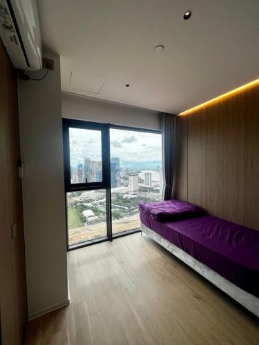 a bedroom with a purple bed and a large window at Vue Aston in Phnom Penh