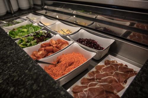 a buffet filled with different types of vegetables and meat at Vincent House London Residence in London