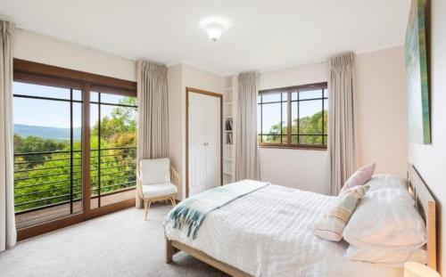 a bedroom with a bed and a large window at Twilight Ridge in Bega