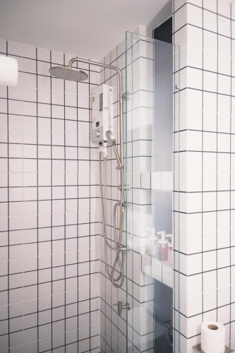 a shower in a bathroom with white tiled walls at Prouds House in Ban Hua Phlong