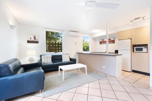 a living room with a couch and a kitchen at Hastings Villas in Noosa Heads