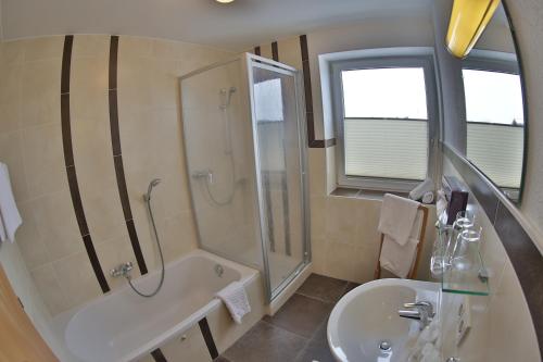a bathroom with a tub shower and a sink at Pension Apartment Hödner in Ebbs