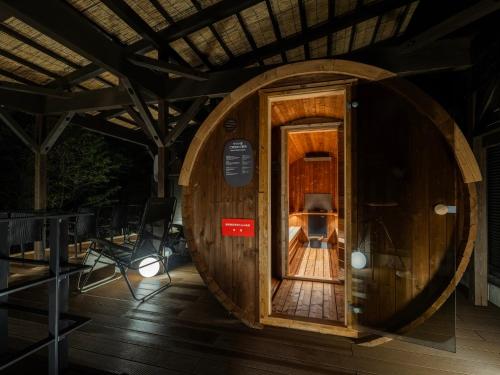 a wooden barrel room with a door in the middle at BbyC HOTEL Kusatsu in Kusatsu