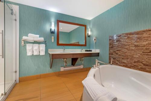 a bathroom with a tub and a sink and a mirror at Comfort Inn & Suites Airport North in Calgary