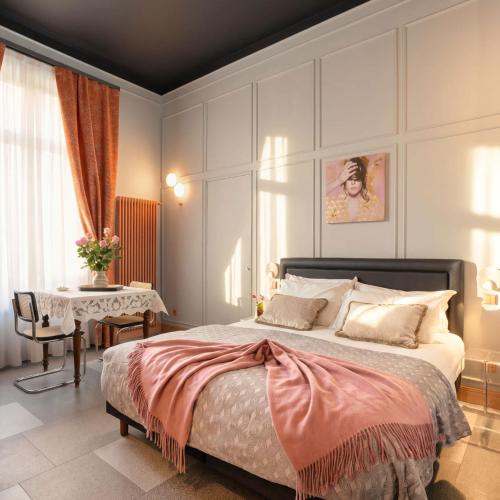 ein Schlafzimmer mit einem großen Bett und einem Tisch in der Unterkunft Homeby, Cinisca Suites in Bologna