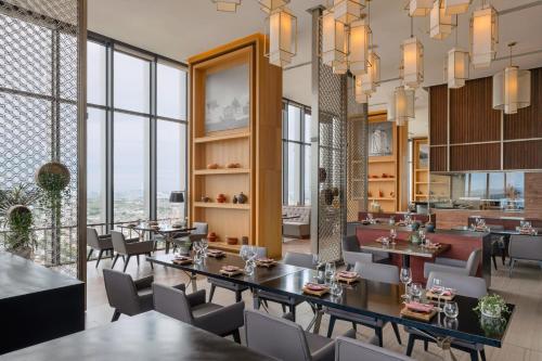 a restaurant with tables and chairs and large windows at Meliá Vinpearl Thanh Hoa in Thanh Hóa