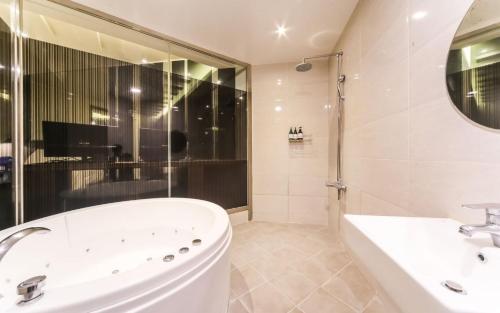 a white bathroom with a tub and a sink at Ulsan Seongnam Hotel Mar in Ulsan