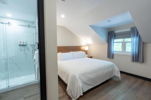 a bedroom with a white bed and a glass shower at Isaiah Tubbs Resort & Conference Centre in Picton