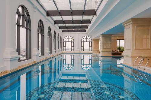 an indoor pool with blue water in a building with windows at Meliá Vinpearl Phu Ly in Phủ Lý