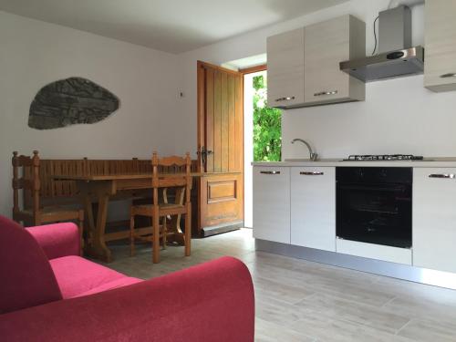 eine Küche und ein Esszimmer mit einem Tisch und einem roten Sofa in der Unterkunft Lake Como Cottage in Gravedona
