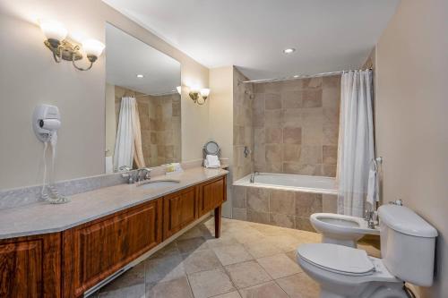 a bathroom with a sink and a toilet and a tub at Manoir Des Sables, an Ascend Collection Hotel in Magog-Orford