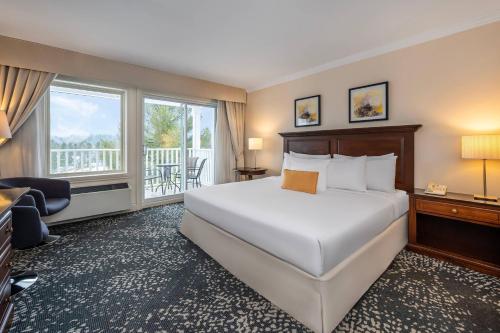 a hotel room with a bed and a balcony at Manoir Des Sables, an Ascend Collection Hotel in Magog-Orford