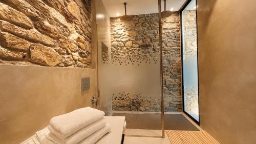 a bathroom with a shower with a stone wall at The Cliff Residences in Plomari
