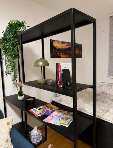 a black book shelf with a desk and a lamp at Sarajevo s Secret -Airport Apartment East Sarajevo in Donje Mladice