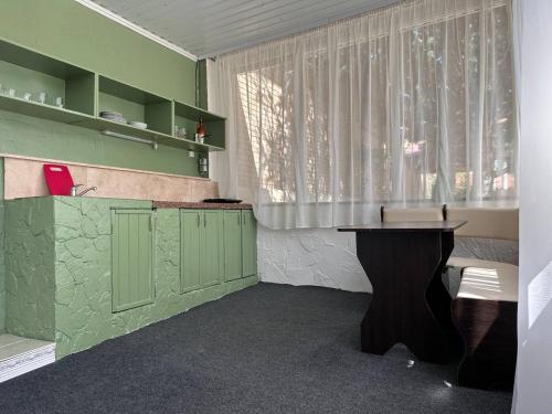 a green room with a table and a window at Гостьовий дім PATRICK in Sanzhiyka