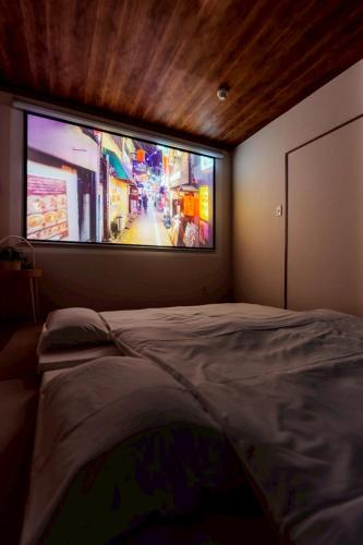 a bedroom with a large tv on the wall at 余韻 -YOIN- Kofu 甲府中心街で夜を楽しむ貸切宿 in Kofu