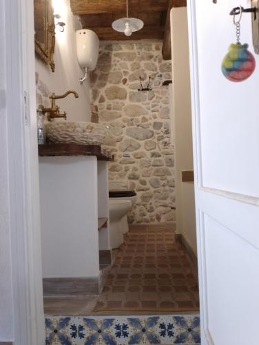 a bathroom with a toilet and a stone wall at La casetta in Trabia