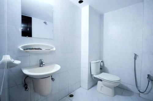 a white bathroom with a toilet and a sink at The White Beach Resort in Cox's Bazar