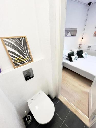 a white bathroom with a toilet and two beds at Stokbrogade 7 - lejlighed 2 in Hjørring