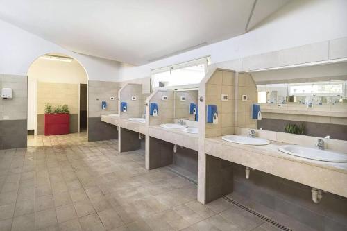 a bathroom with four sinks and a row of mirrors at Camping Bi-Village - Roan in Valbandon