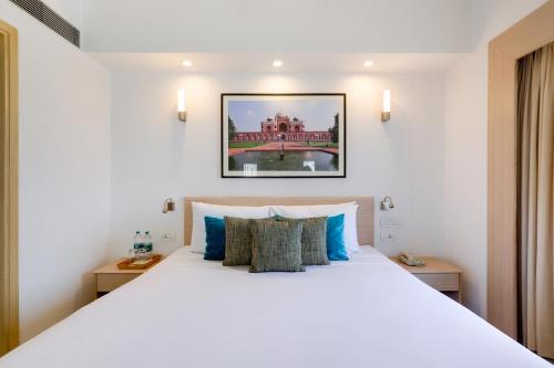 a bedroom with a large white bed with blue pillows at Red Fox by Lemon Tree Hotels, Sector 60, Gurugram in Gurgaon