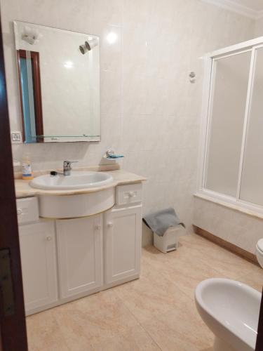 a white bathroom with a sink and a mirror at VIVIENDA TURÍSTICA Bajo, 7 Escaleras in Laxe