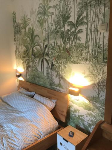 a bedroom with a bed and a wallpaper with palm trees at Côté cour, côté source chambre d'hôtes in Chaudfontaine