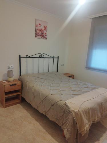a bedroom with a bed and a night stand and a window at VIVIENDA TURÍSTICA Bajo, 7 Escaleras in Laxe
