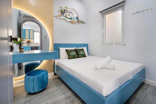 a small bedroom with a blue bed and a blue stool at VILLA NOVAWORLD PHAN THIET Beach in Phan Thiet