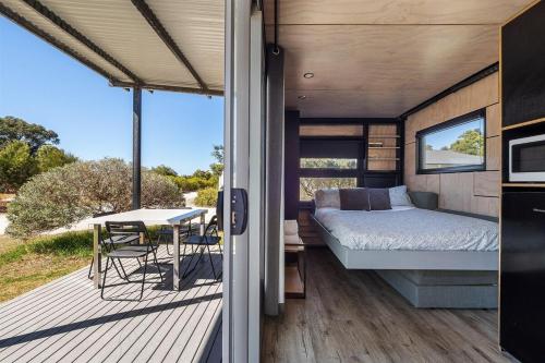 a bedroom and a bed on a deck with a table at Trackside Tiny Home in Augusta