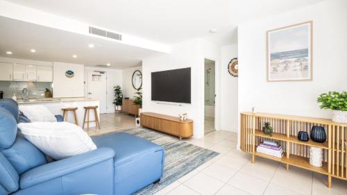a living room with a blue couch and a kitchen at Whispering Waves On Boyd in Woorim